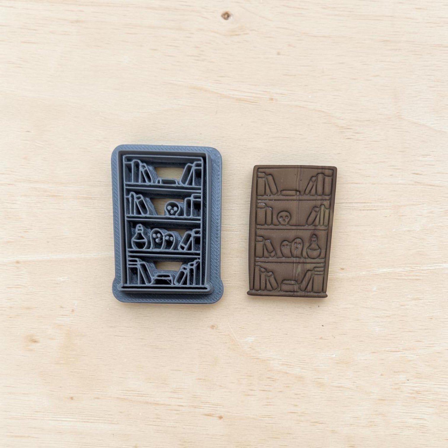 Haunted bookshelf cutter and clay impression – side‑by‑side view of 3D printed cutter and embossed clay result with spooky shelf details.