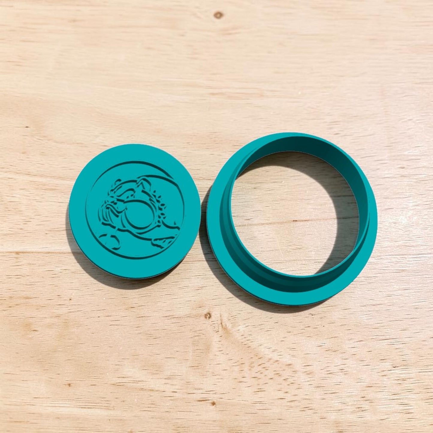 Bulldog mascot stamp and cutter set – teal 3D-printed fondant and clay embossing tools displayed side by side on wood background.