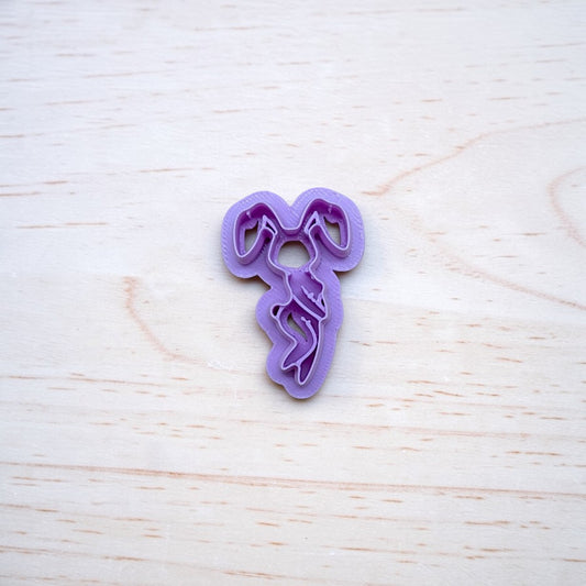 Purple cookie cutter shaped like a sexy bunny rabbit on a light wooden surface