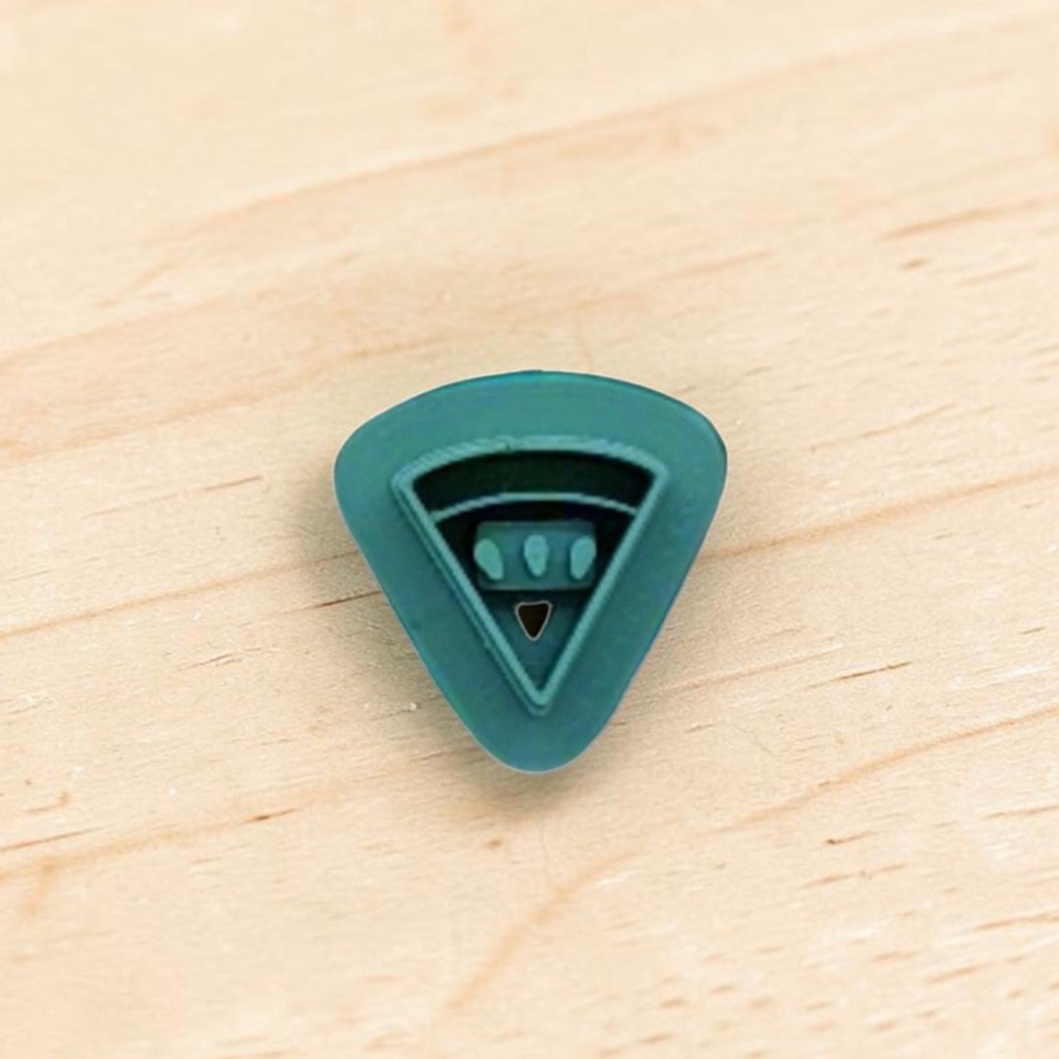 Teal color plastic cutter shaped like a watermelon slice on a wooden surface