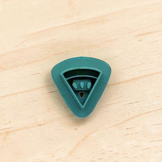 Teal color plastic cutter shaped like a watermelon slice on a wooden surface
